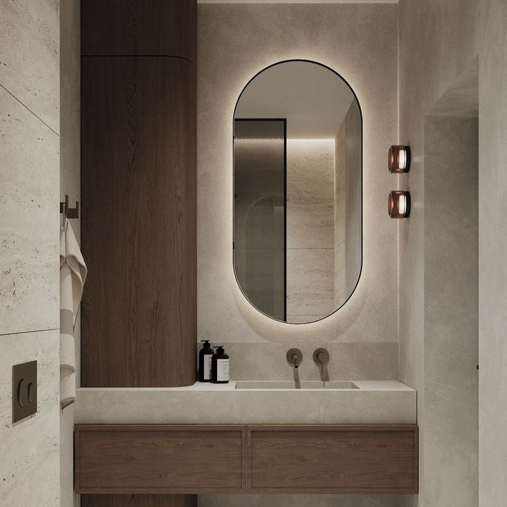 Modern bathroom with wooden vanity, oval mirror, and neutral color scheme.