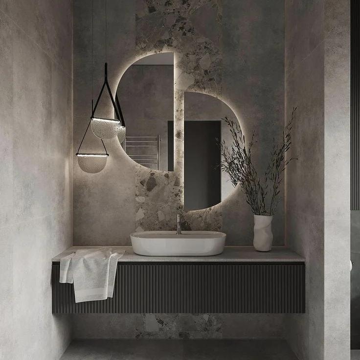 Elise half-moon LED mirror above a modern bathroom vanity. Claris Company.