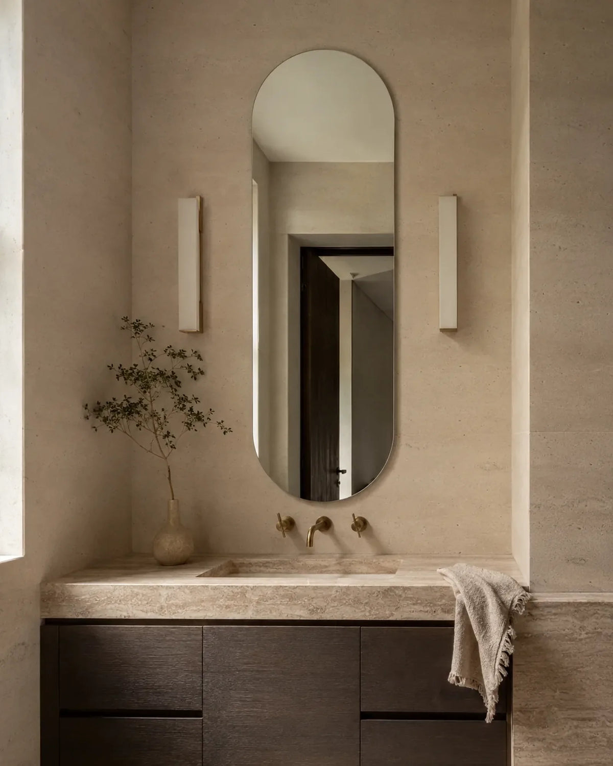 Claris ACUTO oval LED bathroom mirror above a sconce-lit vanity, Concept Studio