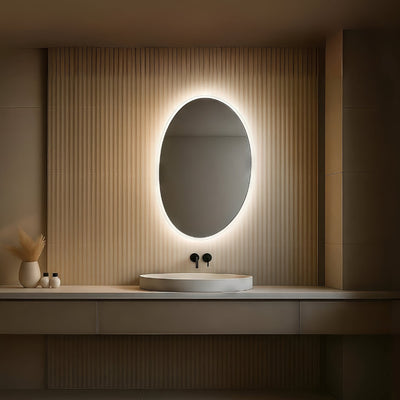 Bathroom vanity with a round illuminated mirror and decorative items.